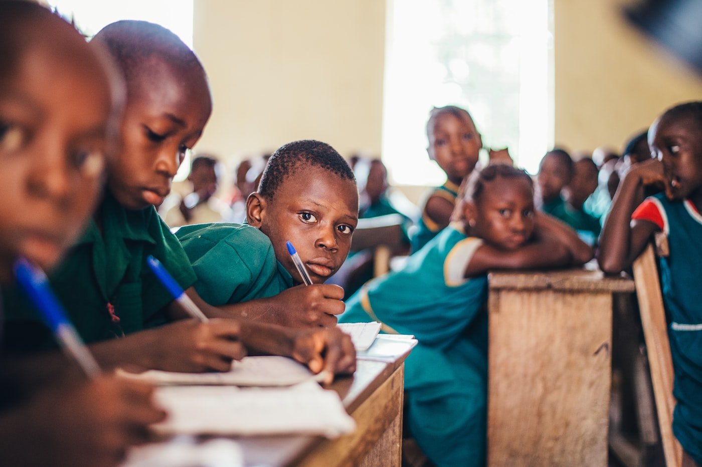 African school children writing in exercise books during class